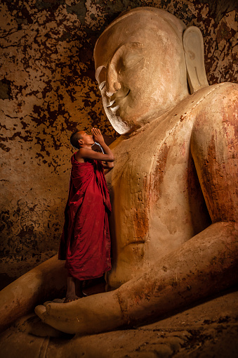Two young buddhist monks praying inside an ancient temple, Bagan, Myanamar