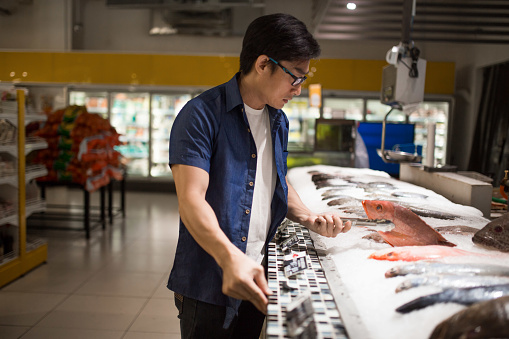 An Asia mature man choosing seafood in supermarket