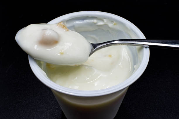 istock Fresh peach yogurt in a white cup isolated on black background 1220509930