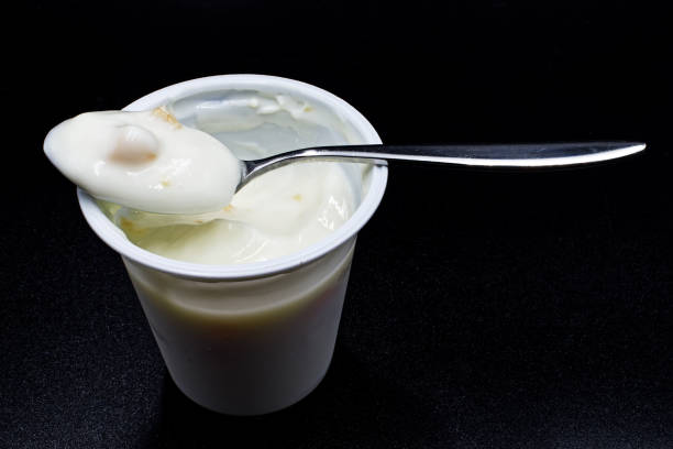 istock Fresh peach yogurt in a white cup isolated on black background 1220510076