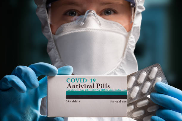 pills for coronavirus treatment - surgical glove human hand holding capsule imagens e fotografias de stock