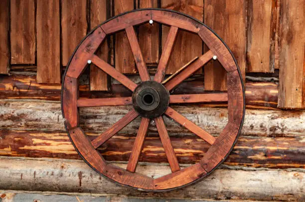 Photo of cart wheel on the wall of a wooden house