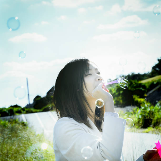 istock A young Japanese woman is playing with soap bubbles under the blue sky. 1220513938