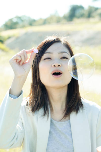 istock A young woman is playing with soap bubbles in the grass on a sunny day. 1220514833