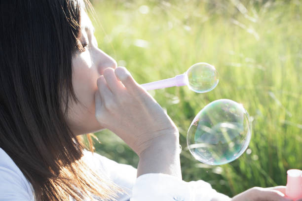 istock A young woman is playing with soap bubbles in the grass on a sunny day. 1220514955