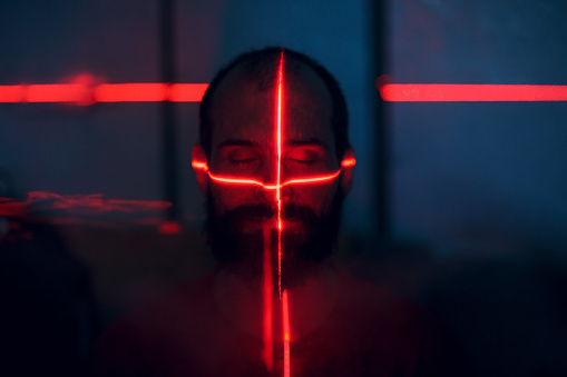 Man in dark with face illuminated by red laser on contour