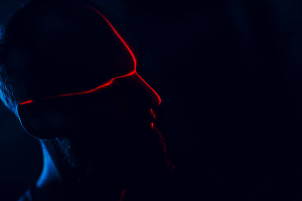 istock Man in dark with face illuminated by red laser on contour 1220515347