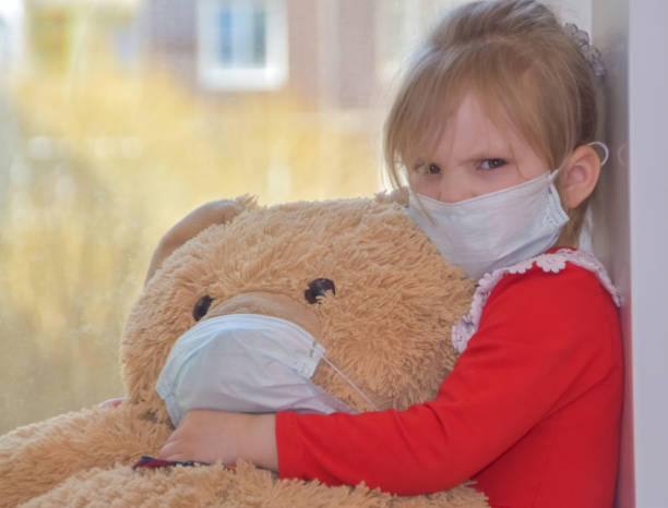 istock child with a toy a bear in a mask at the window looking through a dirty window 1220515520