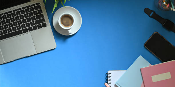 istock Top view image of computer laptop putting on colorful working desk with coffee cup, potted plant, pencils in glass vase, smartphone, note, smartwatch and notebook. Orderly workspace concept. 1220516465