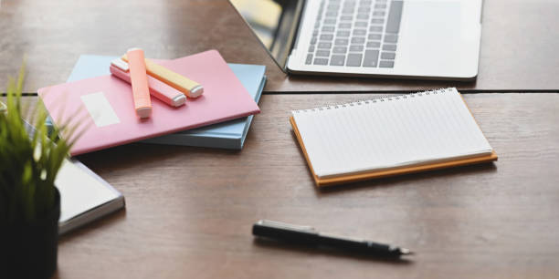 istock Computer laptop putting on wooden working desk and surrounded by notebook, pen, note, marker pens and potted plant over orderly workspace as background. 1220516701