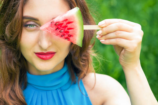 Woman covers eye with watermelon.