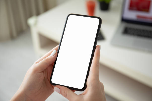 istock female hands holding phone with isolated screen and laptop 1220522053
