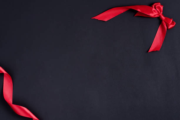 istock Festive black background with corner frame from red ribbon and decorative bow. 1220522624