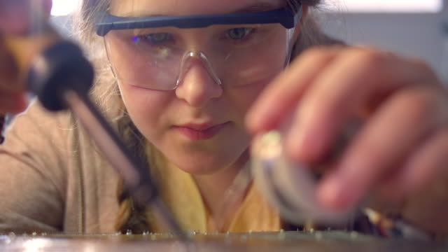 SLO MO Face of a teenage girl repairing the circuit board with soldering iron and wire
