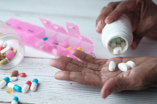 Mujer de edad avanzada vertiendo pastillas de la botella en la mano, vista superior photo