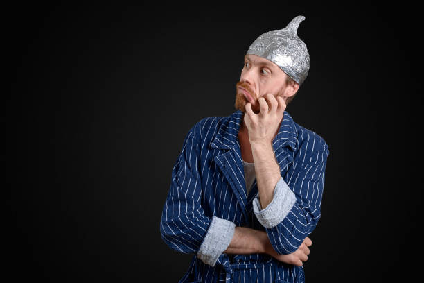 scared man in foil cap and old holey bathrobe scared man in foil cap and old holey bathrobe tin foil hat stock pictures, royalty-free photos & images