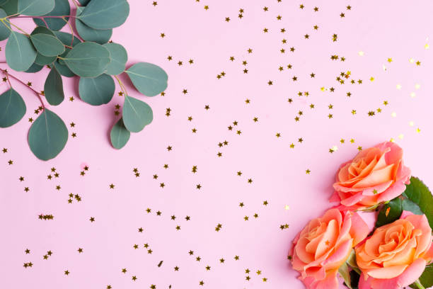 istock Corner deorative frame from roses flowers, Eucalyptus twigs and carnival decorative bright confetti stars on a light pink background. 1220524558