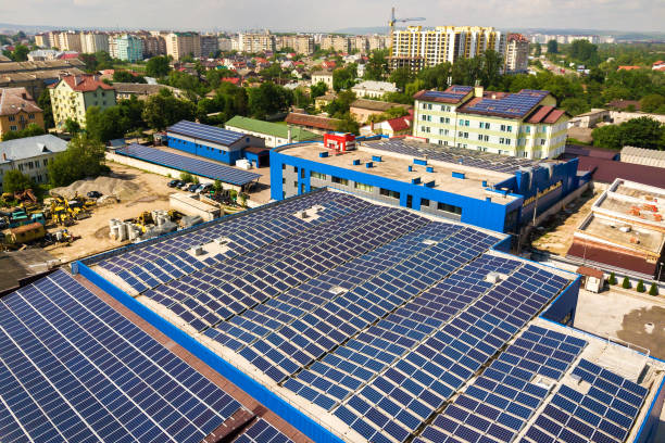 vue aérienne de nombreux panneaux solaires voltaiques photo montés sur le toit du bâtiment industriel. - voltaic photos et images de collection