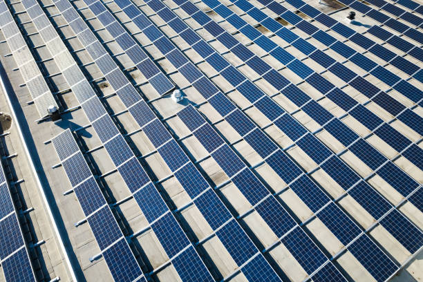vue aérienne de nombreux panneaux solaires voltaiques photo montés sur le toit du bâtiment industriel. - voltaic photos et images de collection