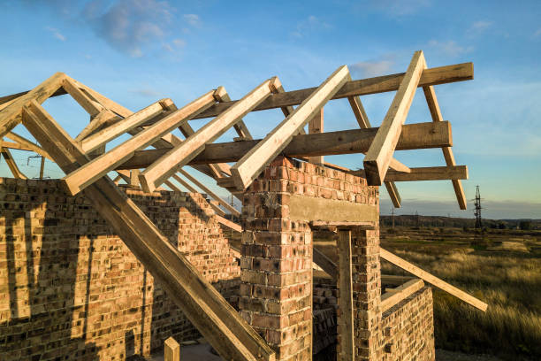 istock Private residential house with wooden roof frame structure under construction. Unfinished brick building under development. 1220526537