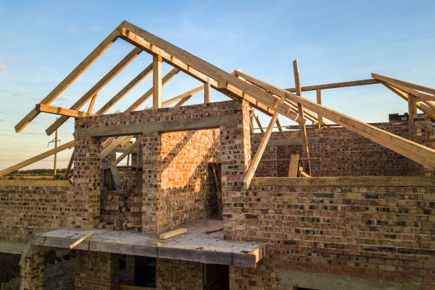istock Private residential house with wooden roof frame structure under construction. Unfinished brick building under development. 1220526546