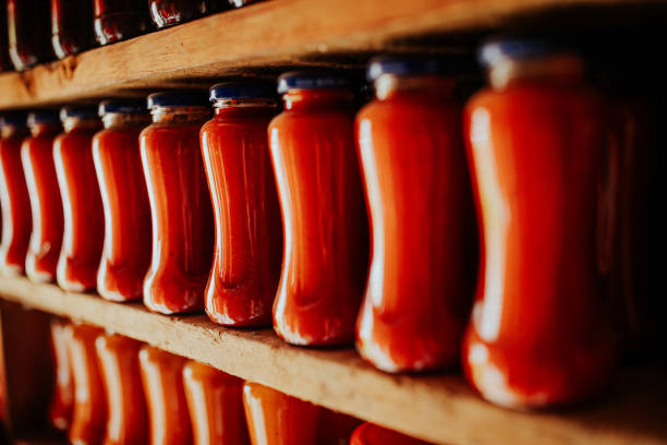 Homemade jam, tomato sauce, juices and pickled in jars on shelves in pantry