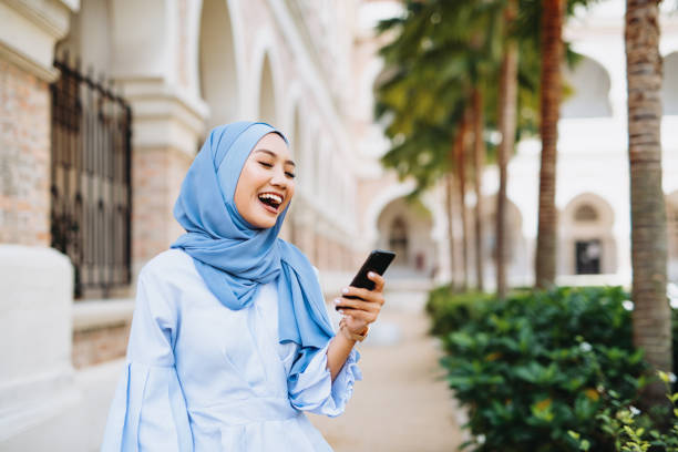 istock Modern muslim woman with hijab using smart phone and online messages 1220529784
