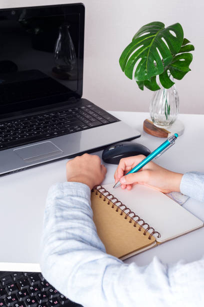 istock Workplace with laptop, boy puple's hands with pan above notebook and green plant on a white table. 1220533620