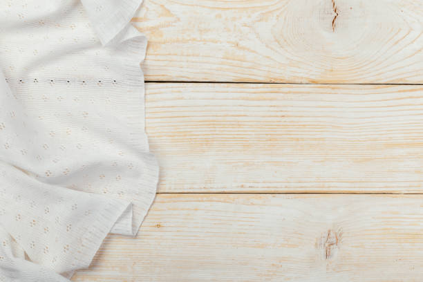 istock Top view on a white wooden table with a linen kitchen towel or textile napkin. a tablecloth on a light wood countertop. Copy space for text. 1220533630