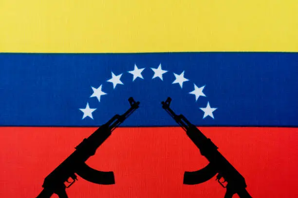 Photo of Several automatic rifles raised up on the background of the Venezuelan flag