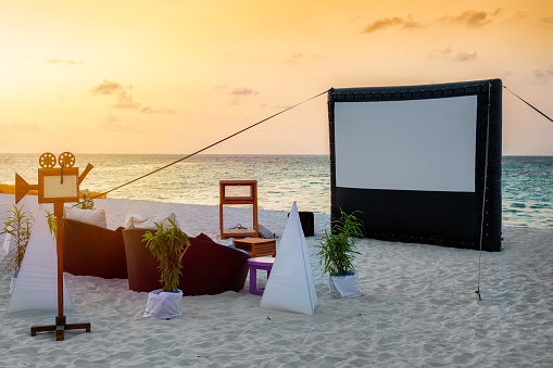 A romantic, private cinema setting on a tropical beach during sunset time
