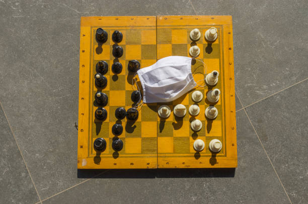 istock White handmade disposable face mask lying lonely on chess board with unfinished chess game because of Coronavirus COVID-19 quarantine period 1220536887
