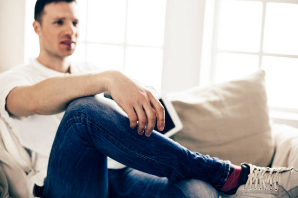 istock young man with a digital tablet sitting on the couch 1220537835