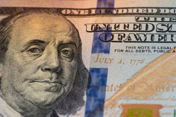 istock one hundred dollar bill with a lit face on a wooden background 1220537874