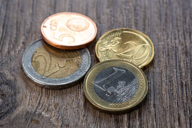 istock Euro coins and one hundred dollars on a wooden background 1220537965