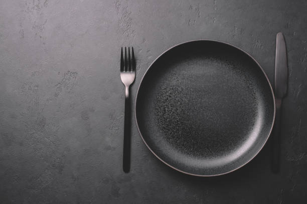 istock Empty black ceramic plate and cutlery on a stone dark table 1220539620