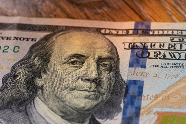 istock one hundred dollar bill with a lit face on a wooden background 1220539918