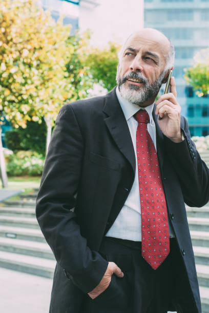istock Bearded businessman talking on phone and looking at distance 1220541358