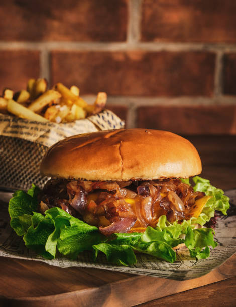 istock Burger with beef and caramelized onions on a wooden board. Cheeseburger with onion and beef. Juicy Delicious Homemade Burger. 1220547036