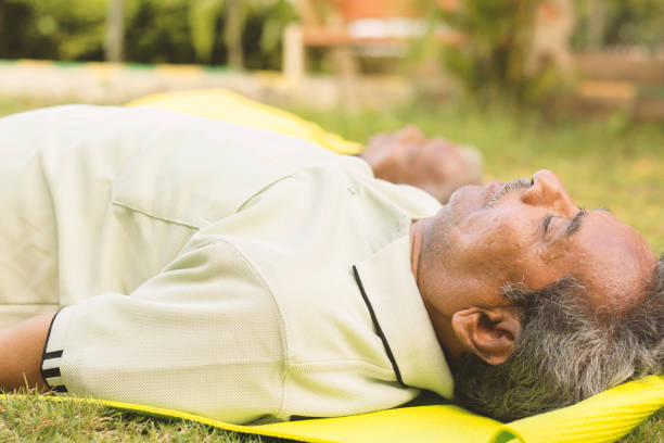 idosos praticando yoga - shavasana ou pose corporal é o fim de uma aula ou prática - yoga para idosos, conceito ativo de idosos saudáveis. - corps - fotografias e filmes do acervo