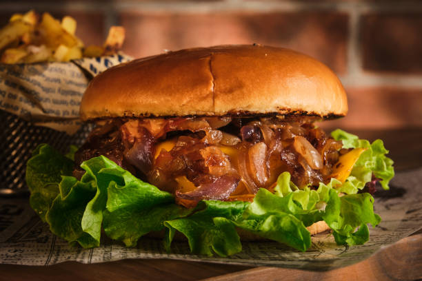 istock Burger with beef and caramelized onions on a wooden board. Cheeseburger with onion and beef. Juicy Delicious Homemade Burger. 1220550016