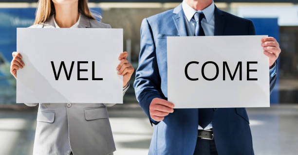Two people holding signs at airport reading welcome