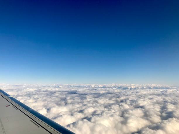 high up in the stratosphere, close to heaven: above the white clouds on a scenic journey in an airplane flight of a vacation journey seeing the aircraft wing gliding over the bright cloudscape - earth stratosphere space planet imagens e fotografias de stock