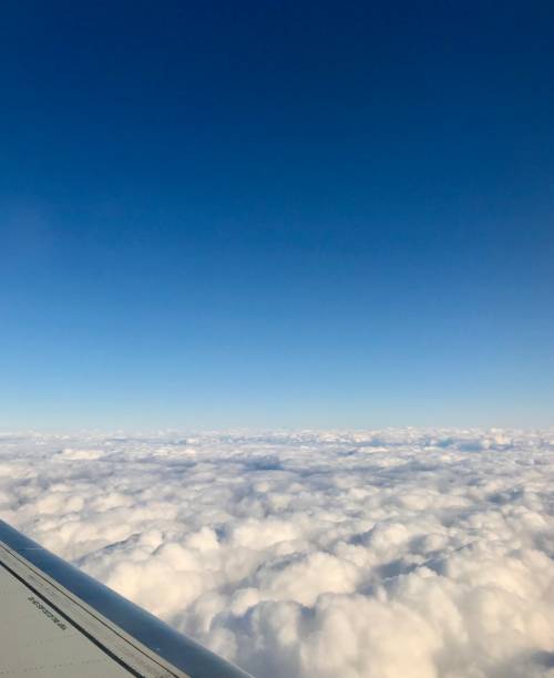 high up in the stratosphere, close to heaven: above the white clouds on a scenic journey in an airplane flight of a vacation journey seeing the aircraft wing gliding over the bright cloudscape - cloud cloudscape stratosphere above imagens e fotografias de stock