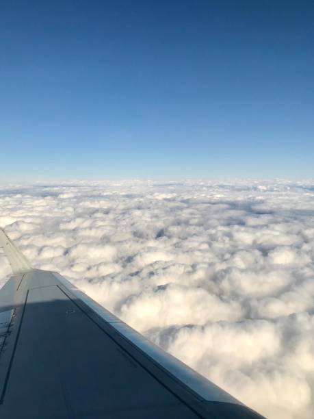 high up in the stratosphere, close to heaven: above the white clouds on a scenic journey in an airplane flight of a vacation journey seeing the aircraft wing gliding over the bright cloudscape - earth stratosphere space planet imagens e fotografias de stock