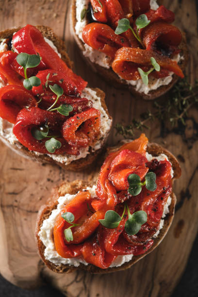 sanduíche com queijo macio e pimentão vermelho assado em uma tábua de madeira. - antipasto roasted pepper bell pepper pepper - fotografias e filmes do acervo