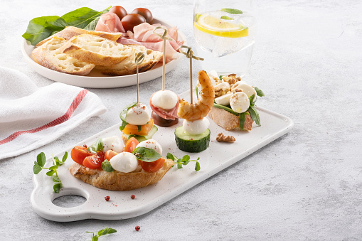 Traditional spanish tapas appetizer. Pinchos with mozzarella, cucumbers, shrimp and prosciutto