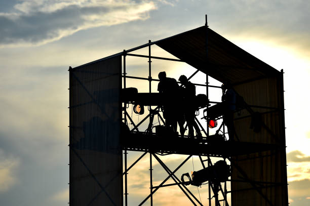 istock Technical staff and equipment silhouetted against sunset light preparing for a music concert 1220552944