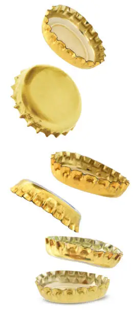 Gold metal beer bottle caps are falling isolated on white