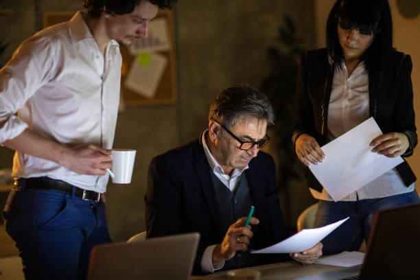 istock Business team working on graphs in office late at night 1220555361
